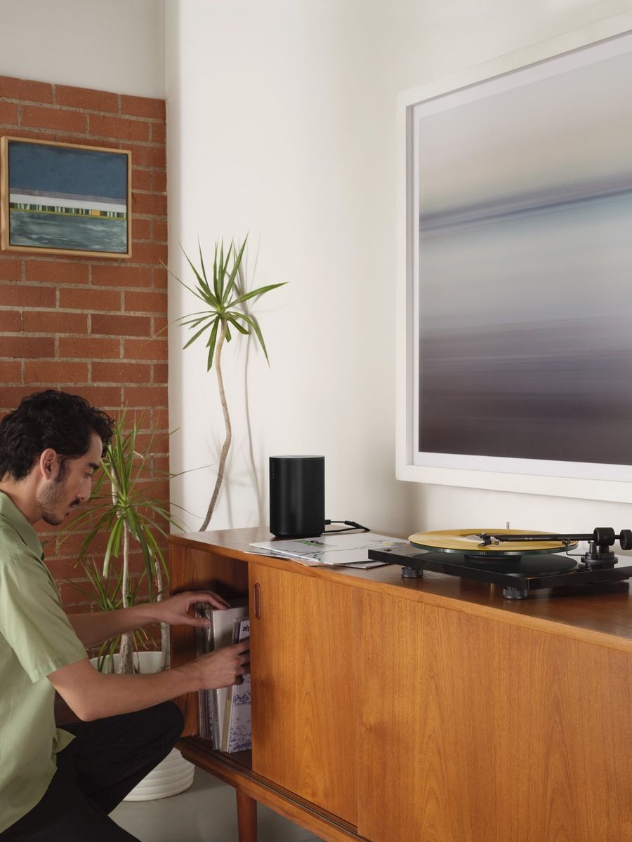 Wireless speaker on a console next to a turntable in a living room